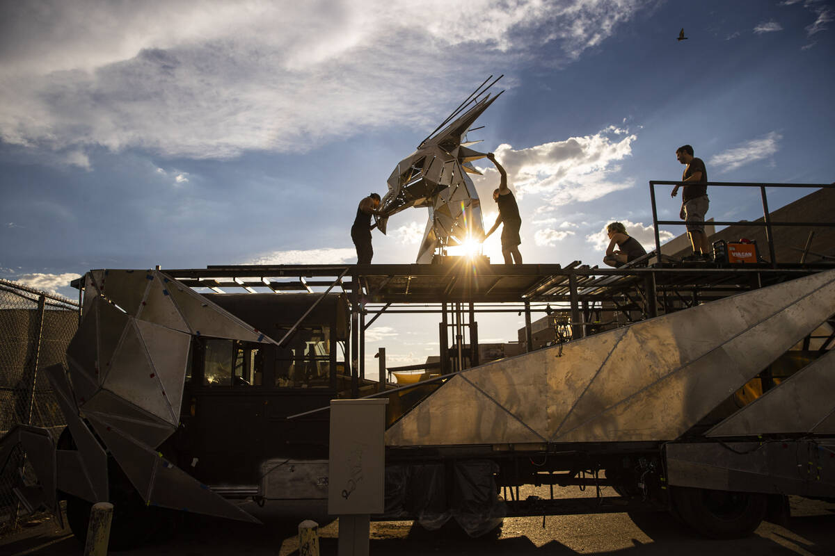 Crew members work to mount the head on The Metaphoenix art car, in preparation for Burning Man, ...