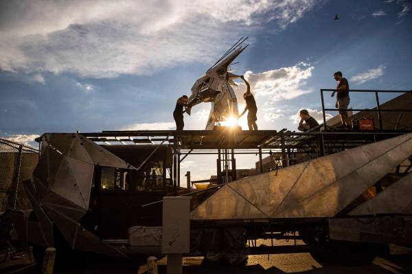 Crew members work to mount the head on The Metaphoenix art car, in preparation for Burning Man, ...