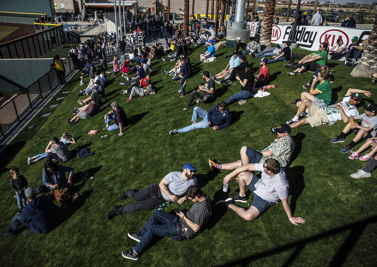 Fans watch the Cleveland Indians play the Oakland Athletics from the right field grass during a ...