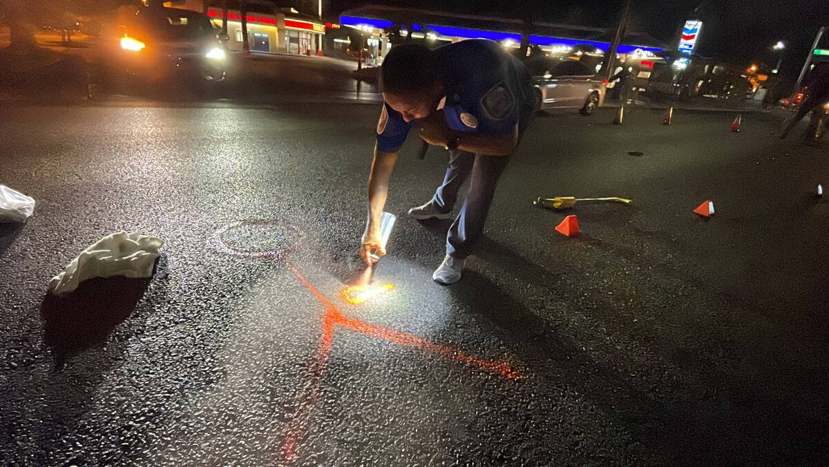 Officer Andy Navarro draws an orange stick figure at the spot where a pedestrian came to rest a ...