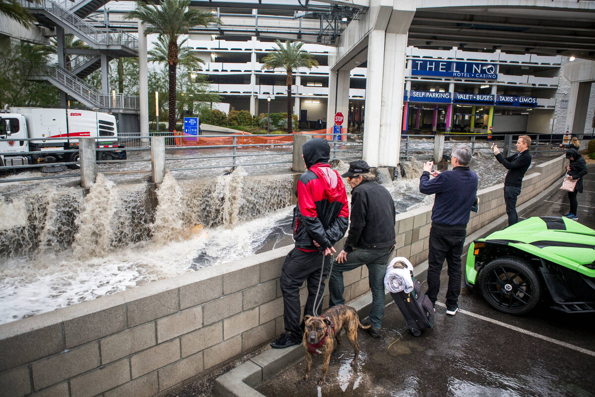 People watch flood waters rush by in a flood channel near The Linq Hotel in Las Vegas on Tuesda ...