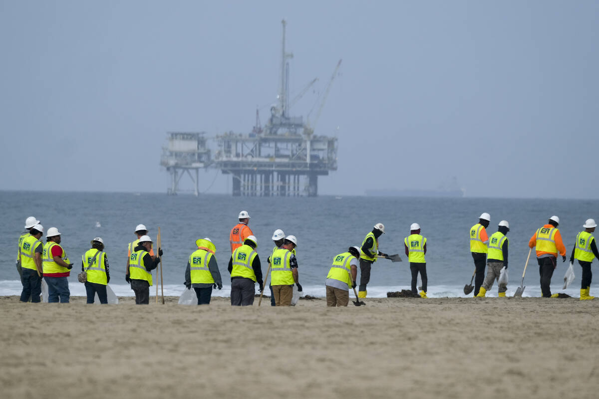 FILE - Workers in protective suits continue to clean the contaminated beach with a platform in ...