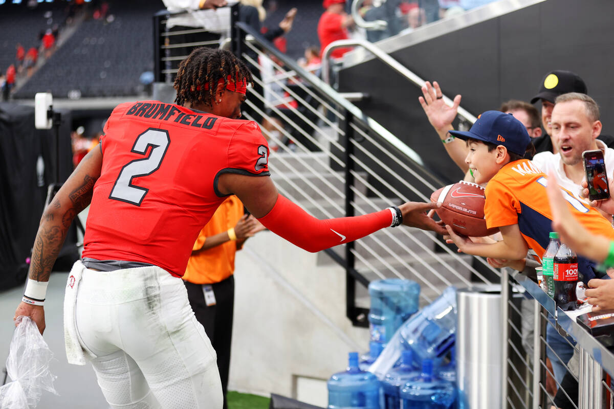 UNLV Rebels quarterback Doug Brumfield (2) hands a ball to 8-year-old Ezra Huitron, 8, of Las V ...