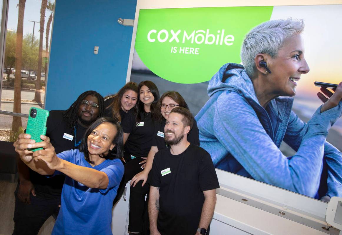 Janet Uthman, market vice-president at Cox Communications, takes a selfie with retail employees ...