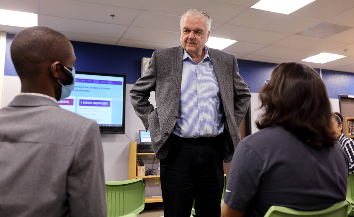 Gov. Steve Sisolak, center, visits with Clark High School seniors Amino Nkwethat, left, and Wyl ...