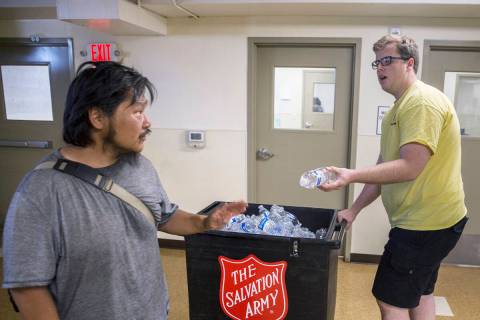 Shelter monitor Boston Brimhall, right, hands out water at a cooling station at The Salvation A ...