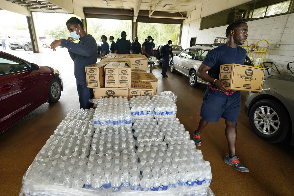 Firefighters and recruits for the Jackson, Miss., Fire Department carry cases of bottled water ...