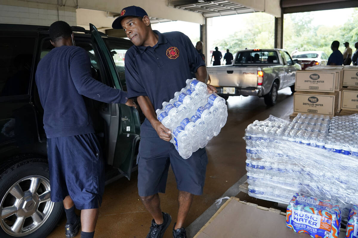 A Jackson, Miss., Fire Department firefighter puts cases of bottled water in a resident's SUV, ...