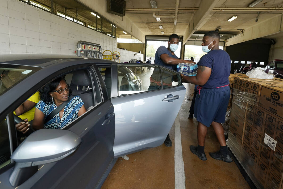 Recruits for the Jackson, Miss., Fire Department place cases of bottled water in a resident's c ...