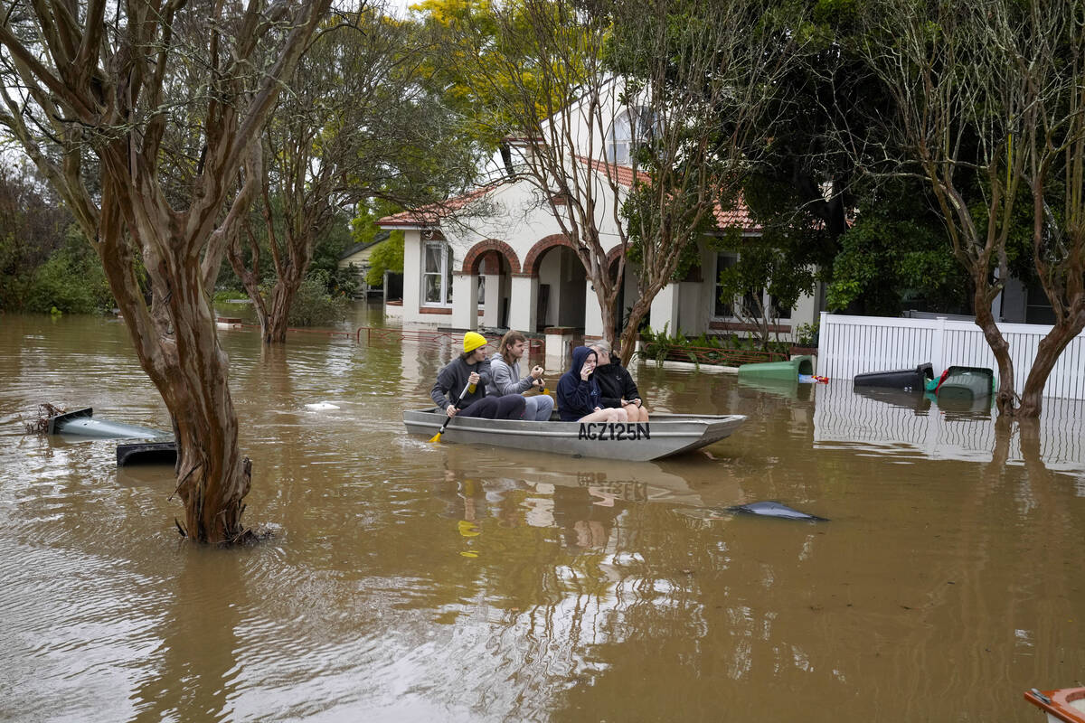 FILE - People paddle through a flooded street at Windsor on the outskirts of Sydney, Australia, ...