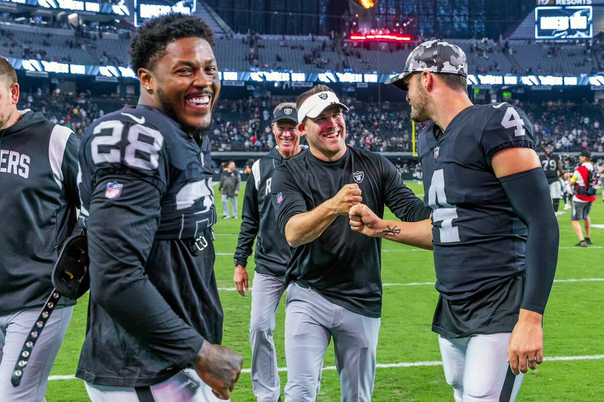 Raiders running back Josh Jacobs (28) smiles as Head Coach Josh McDaniels celebrates with quart ...