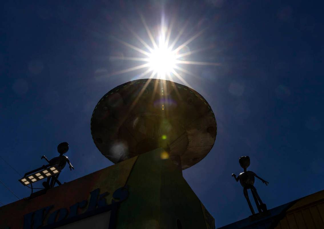 FILE - The afternoon sun light rays pierce through a metal Aliens sculpture and their craft out ...