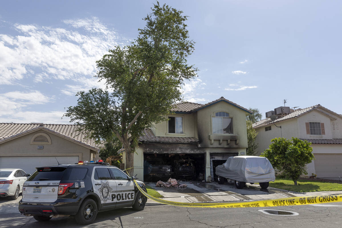 Metropolitan police remain at the scene of a house fire that was extinguished by fire crews in ...