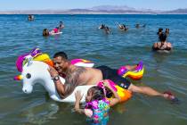Jon Quenga relaxes atop of a unicorn float as Damari Evangelista, 8, hangs on along the shoreli ...