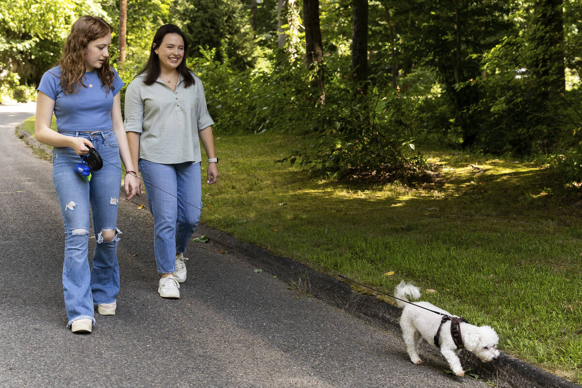 Liv Doscher and her sister Phoebe walk their dog Toby, Tuesday, Aug. 16, 2022, in Sandy Hook, C ...