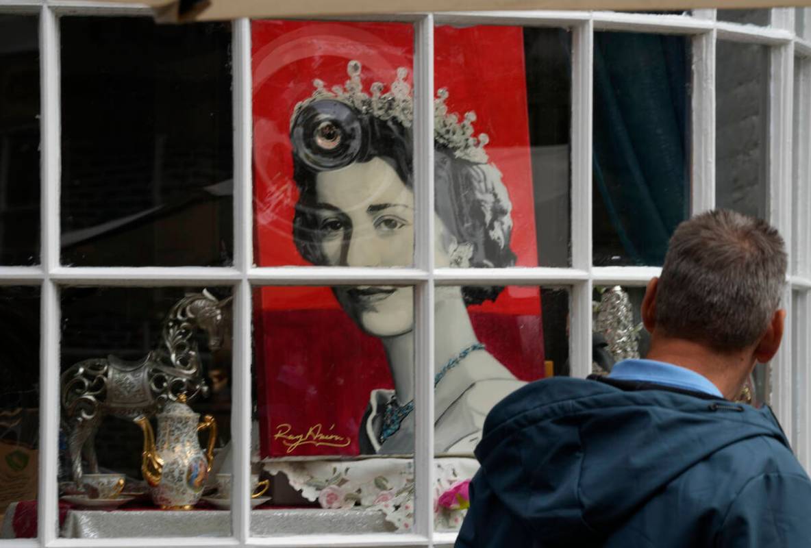 A man looks at a portrait of Queen Elizabeth II in a shop window near Windsor Castle in Windsor ...