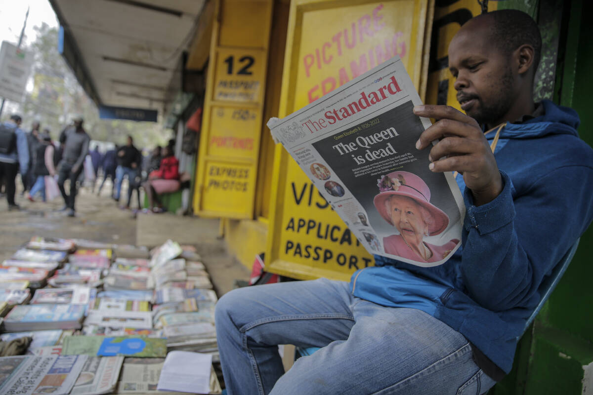 A vendor reads a newspaper showing coverage of the death of Queen Elizabeth II, in downtown Nai ...