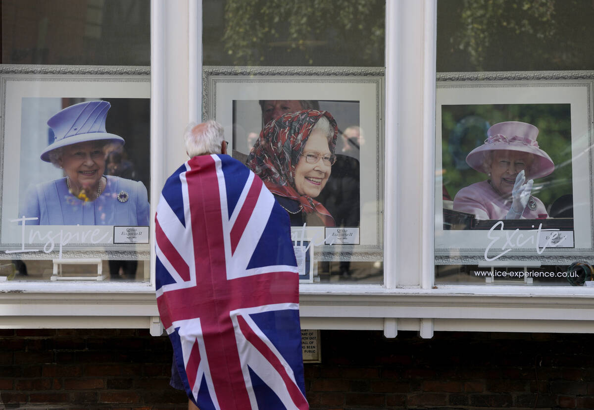 A man looks at framed portraits of Queen Elizabeth II in a shop window near Windsor Castle in W ...