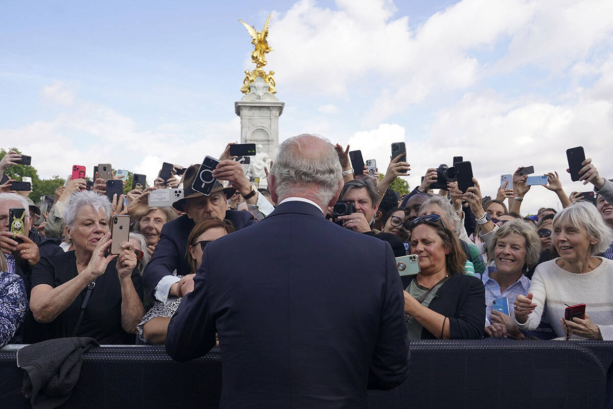 Britain's King Charles III, back to camera, greets well-wishers as he walks by the gates of Buc ...