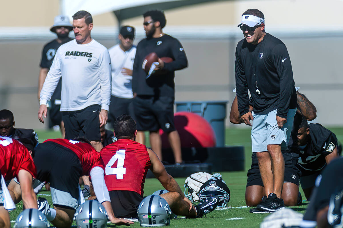 Raiders head coach Josh McDaniels laughs while talking with quarterback Derek Carr (4) during t ...