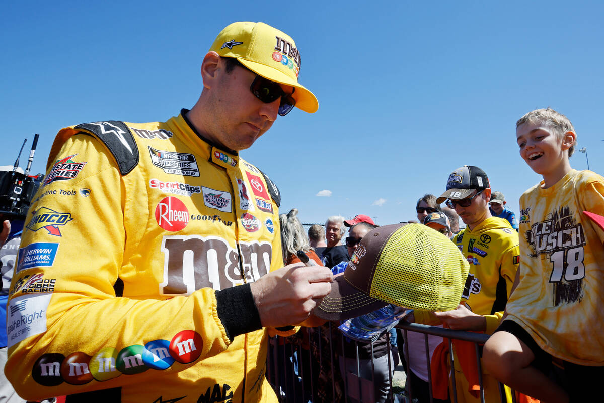 Kyle Busch signs autographs before a NASCAR Cup Series auto race at Kansas Speedway in Kansas C ...