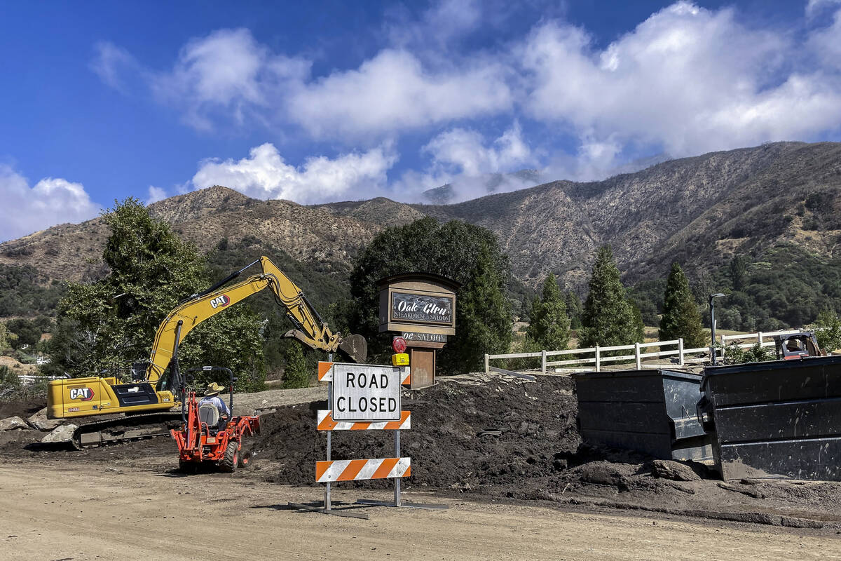 Heavy machinery clears the aftermath of a slow-moving black river of sludge in Oak Glen, Calif. ...