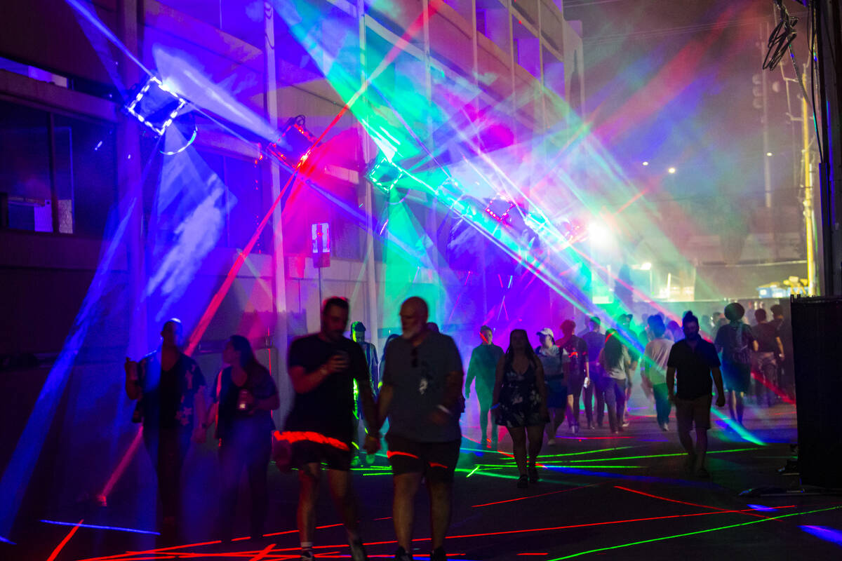 Attendees walk through an alleyway with projected lights during the Life is Beautiful festival ...