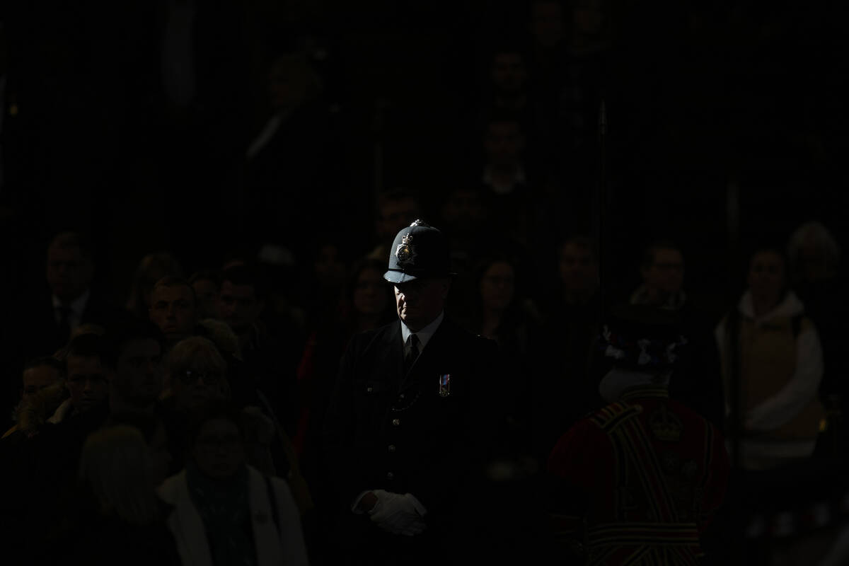 A ray of sun shines on a police officer as he stands guard near the coffin of Queen Elizabeth I ...