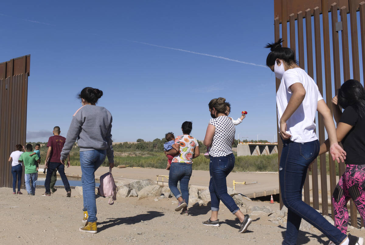 A group of Brazilian migrants make their way around a gap in the U.S.-Mexico border in Yuma, Ar ...