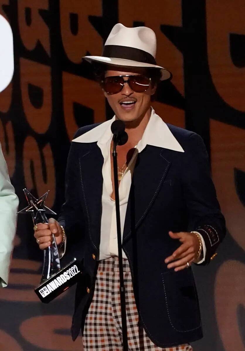 Bruno Mars is shown accepting the award for Album of the Year for "An Evening with Silk Sonic" ...
