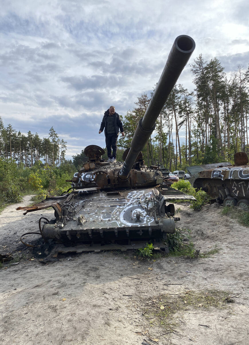 A man walks on top of a damaged Russian tank on Sunday, Sept. 25, in Dmytrivka, outside the Ukr ...
