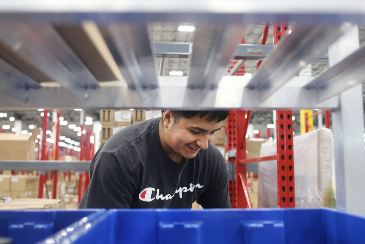 Warehouse associate assistant Enrique Roman prepares individual products to be sorted at the Se ...