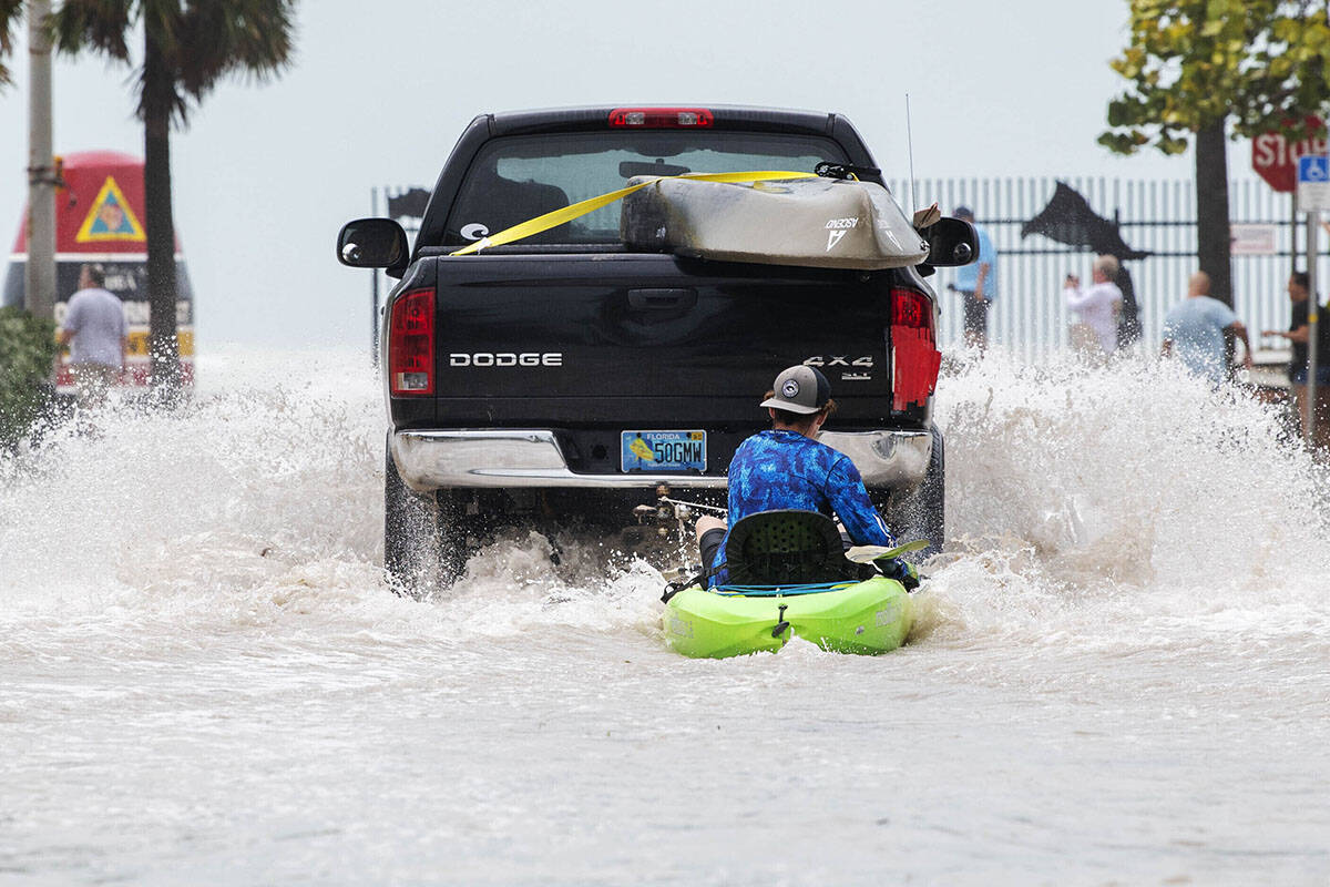 A truck pulls a man on a kayak on a low-lying road after flooding in the aftermath of Hurricane ...