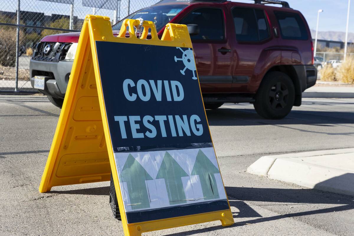 An employee at the Clark County School District building drives past a COVID testing sign on Ja ...