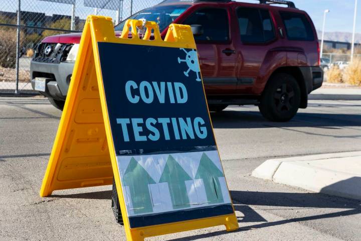 An employee at the Clark County School District building drives past a COVID testing sign on Ja ...