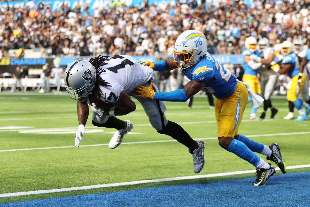 Raiders wide receiver Davante Adams (17) makes a catch for a touchdown under pressure from Los ...