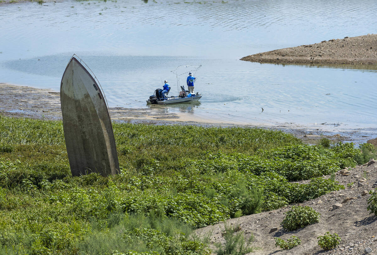 FILE - Men fish near a boat sticking up along the shoreline in Government Wash which is now sur ...
