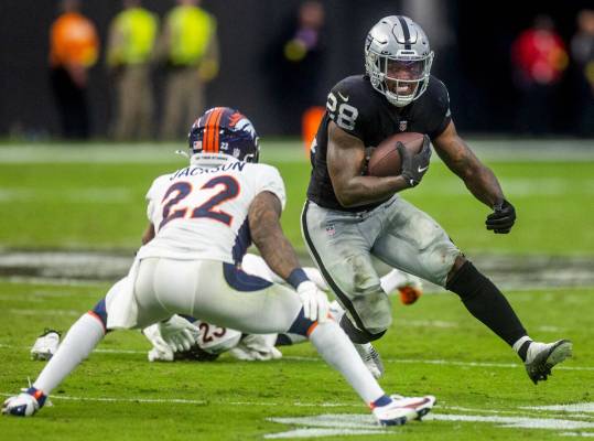 Raiders running back Josh Jacobs (28) readies to take on tackle attempt by Denver Broncos safet ...