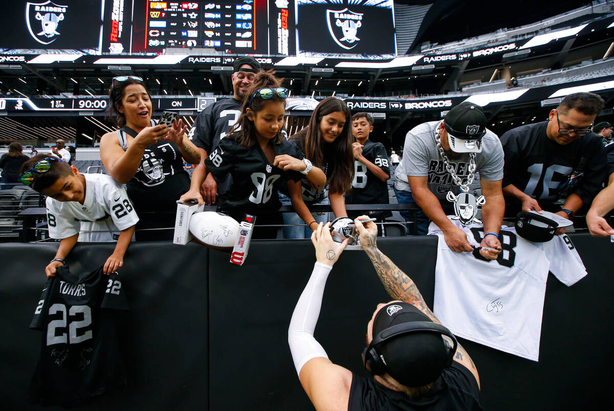 Raiders defensive end Maxx Crosby signs autographs for fans before the start of an NFL game aga ...
