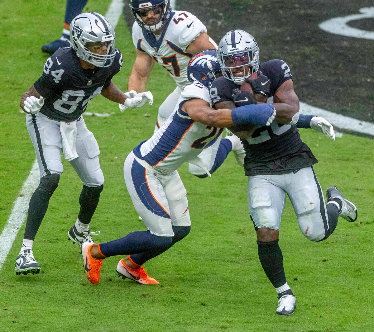 Raiders running back Josh Jacobs (28) takes on contract by Denver Broncos cornerback K'Waun Wil ...
