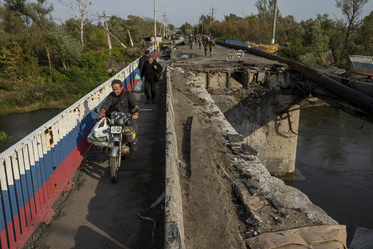 A man drives by motorbike on a destroyed bridge across Oskil river during evacuation in recentl ...