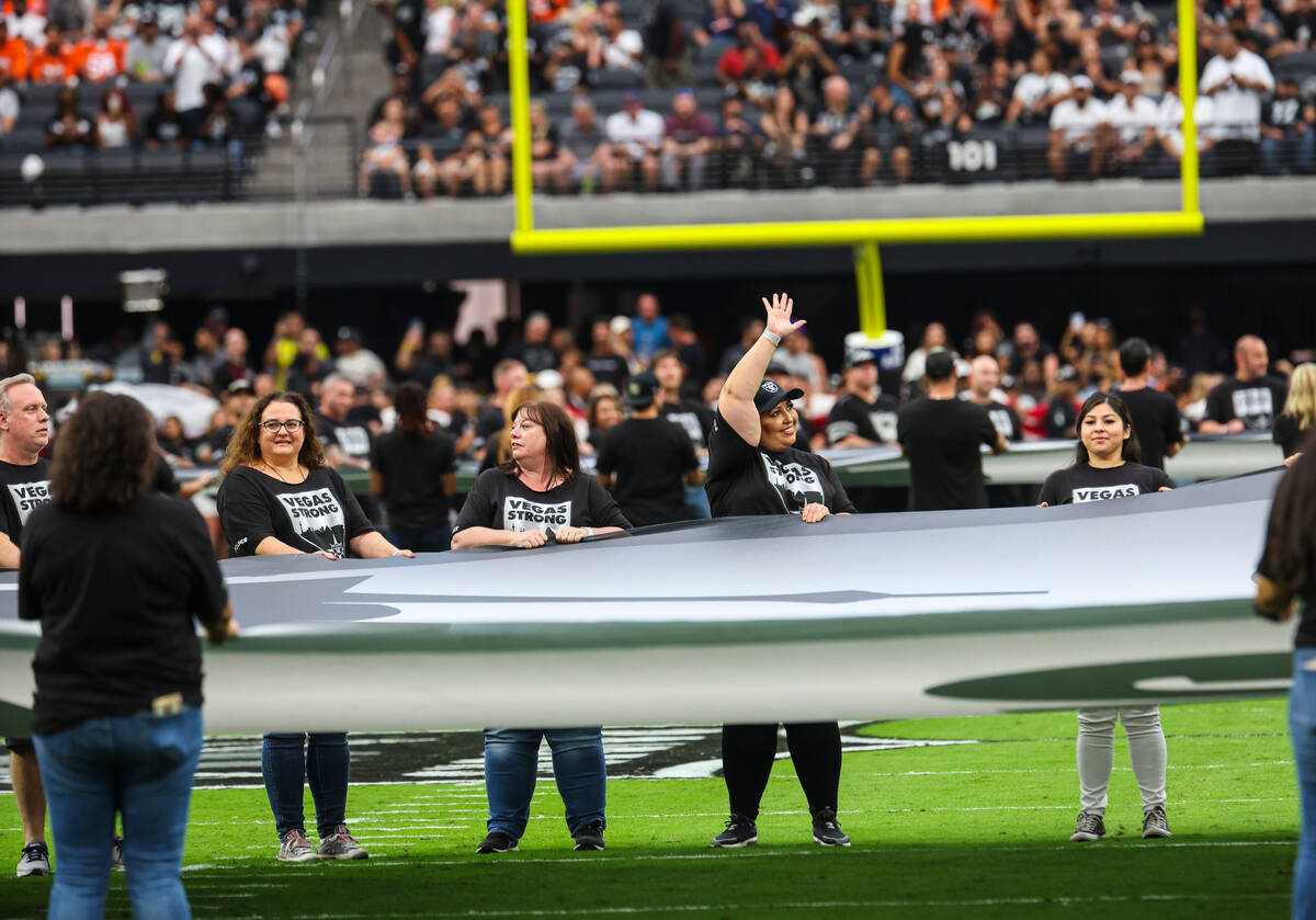 People carry out a Vegas Strong flag before the start of an NFL game between the Raiders and De ...