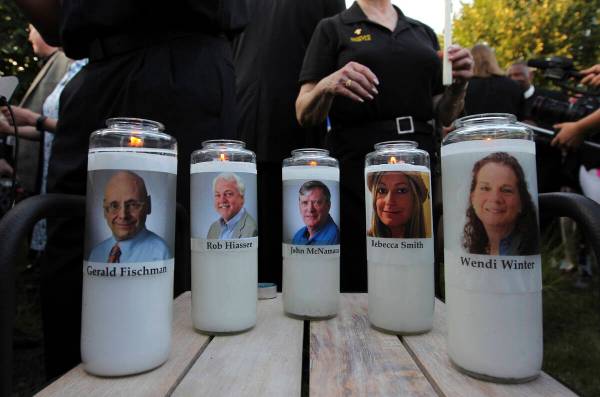 Photos of five journalists adorn candles during a vigil across the street from where they were ...