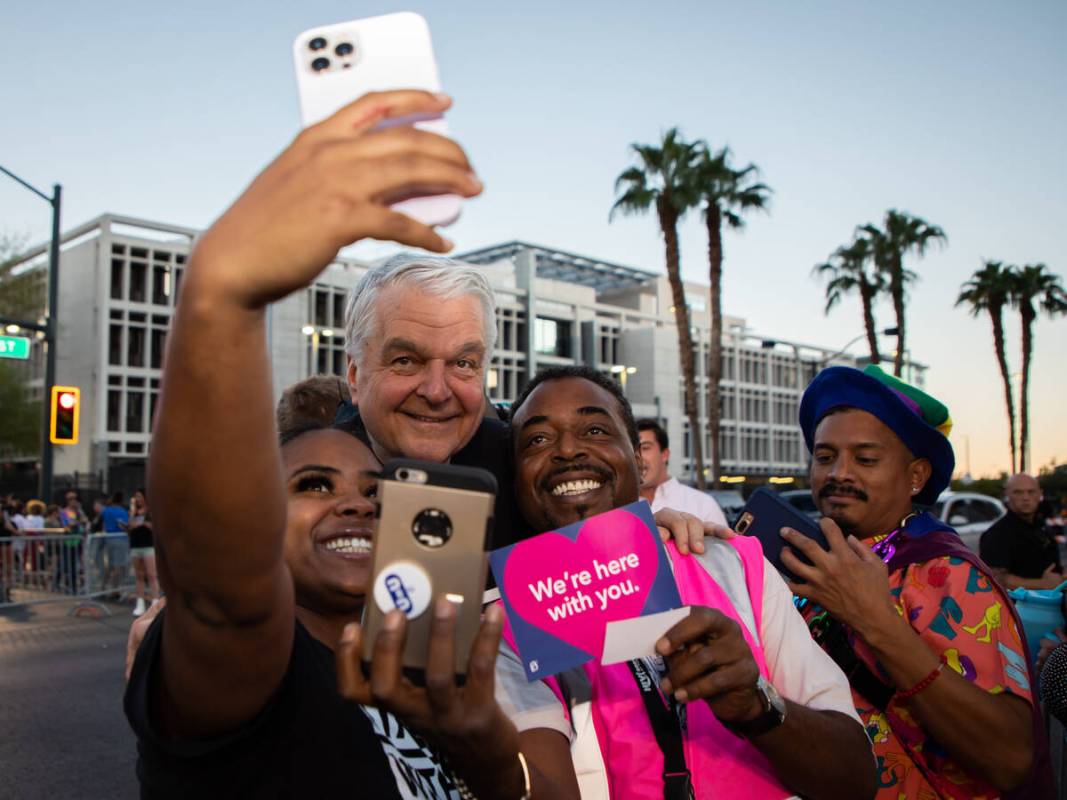 Tiana Jones, left, and Robert Thurmond, right, take a selfie with Gov. Steve Sisolak during the ...