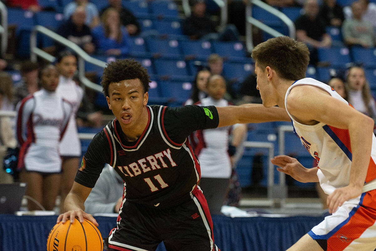 Dedan Thomas Jr of Liberty High School dribbles into defender Ryder Elisaldez of Bishop Gorman ...