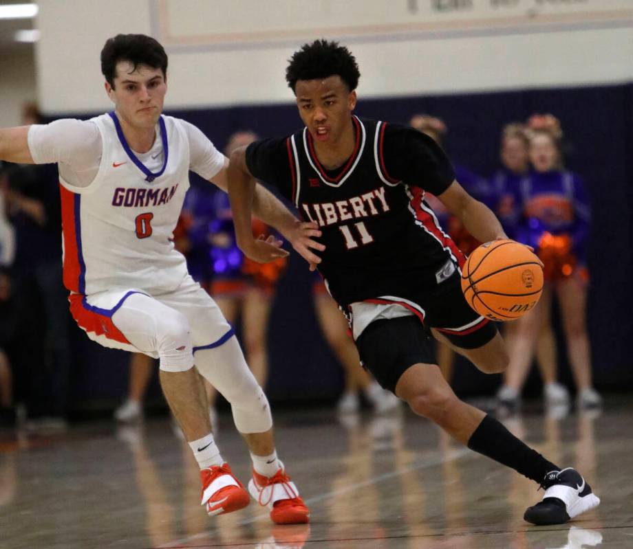 Liberty High School's Dedan Thomas (11) drives past Bishop Gorman High School's Ryan Abelman (0 ...