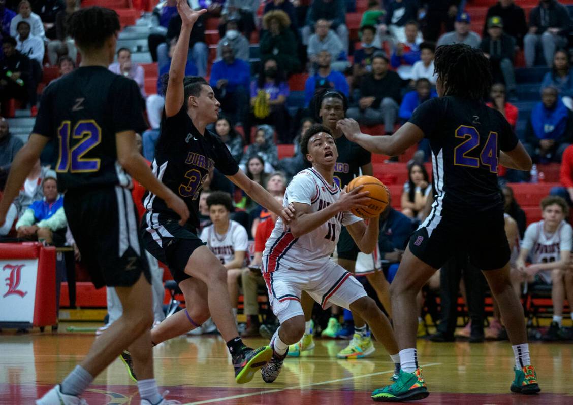 Liberty’s Dedan Thomas (11) drives around Durango’s Sterling Knox (32) and Taj ...