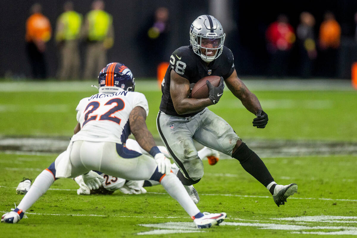 Raiders running back Josh Jacobs (28) readies to take on tackle attempt by Denver Broncos safet ...