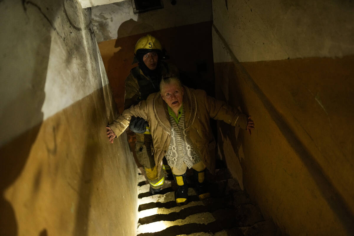 A woman is helped by a Ukrainian firefighter to leave a shelter after a Russian shelling in Kha ...