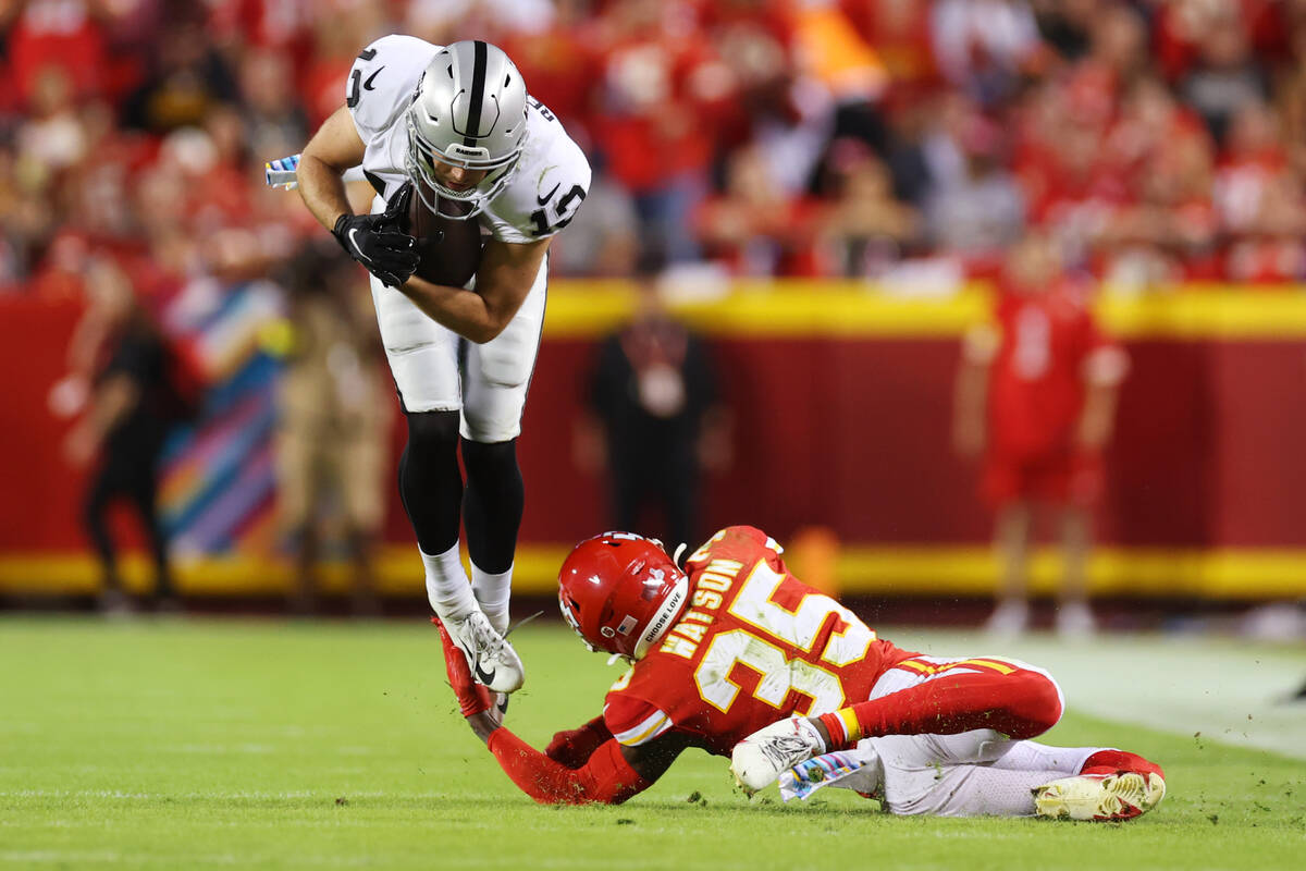 Raiders wide receiver Hunter Renfrow (13) leaps over a tackle attempt by Kansas City Chiefs cor ...